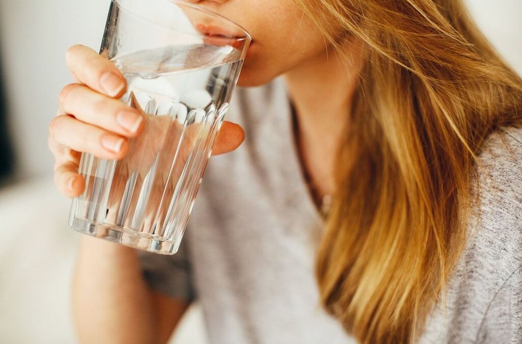 a woman drinking one of her 8 glasses of water